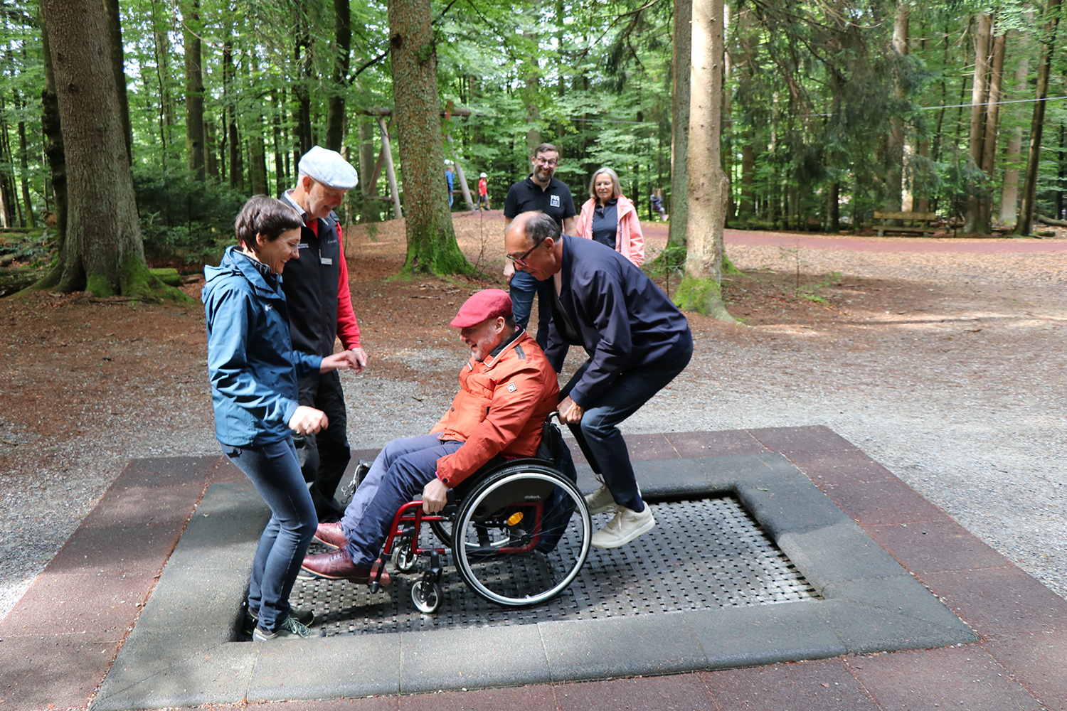 Holger Kiesel, der Behindertenbeauftragte der Bayerischen Staatsregierung (Mitte), probierte zusammen mit Nationalparkleiterin Ursula Schuster (v.l.), Umweltbildungsmitarbeiter Lukas Laux und stellvertretendem Landrat Franz Brunner ein Trampolin aus, dass auch für Rollstuhlfahrer konzipiert ist. Mit dabei waren Christian Fiebig vom Landratsamt und die ehemalige Behindertenbeauftragte Anita Moos (hinten). (Foto: Annette Nigl / Nationalpark Bayerischer Wald) Holger Kiesel, der Behindertenbeauftragte der Bayerischen Staatsregierung (Mitte), probierte zusammen mit Nationalparkleiterin Ursula Schuster (v.l.), Umweltbildungsmitarbeiter Lukas Laux und stellvertretendem Landrat Franz Brunner ein Trampolin aus, dass auch für Rollstuhlfahrer konzipiert ist. Mit dabei waren Christian Fiebig vom Landratsamt und die ehemalige Behindertenbeauftragte Anita Moos (hinten). (Foto: Annette Nigl / Nationalpark Bayerischer Wald)