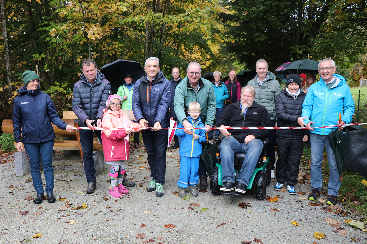 Bürgermeister Gerd Lorenz (v.l.), Landrat Dr. Ronny Raith, Schulleiter Anton Naegeli, Günter Sellmayer und stellvertretender Nationalparkleiter Josef Wanninger durchschnitten zusammen mit Schülerinnen und Schülern traditionell ein Band und gaben den Weg frei. Mit dabei waren auch VdK-Kreisgeschäftsführer und stellvertretender Landrat Helmut Plenk (2. Reihe v.r.), Landtagsabgeordneter Martin Behringer sowie Naturpark-Vorsitzender Georg Bauer. (Foto: Nationalpark Bayerischer Wald) Bürgermeister Gerd Lorenz (v.l.), Landrat Dr. Ronny Raith, Schulleiter Anton Naegeli, Günter Sellmayer und stellvertretender Nationalparkleiter Josef Wanninger durchschnitten zusammen mit Schülerinnen und Schülern traditionell ein Band und gaben den Weg frei. Mit dabei waren auch VdK-Kreisgeschäftsführer und stellvertretender Landrat Helmut Plenk (2. Reihe v.r.), Landtagsabgeordneter Martin Behringer sowie Naturpark-Vorsitzender Georg Bauer. (Foto: Nationalpark Bayerischer Wald)